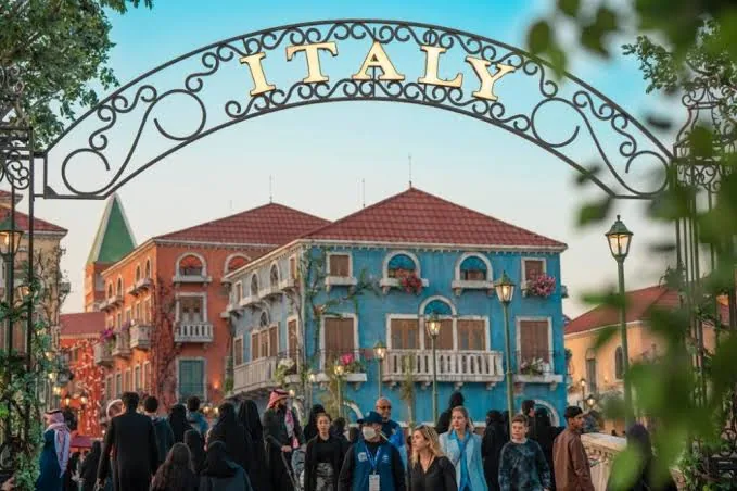 قوس مدخل ITALY الحديدي والزوار عند الغسق — المنطقة الإيطالية ببوليفارد ورلد / ITALY wrought-iron entrance arch with visitors at twilight — Boulevard World Italian zone