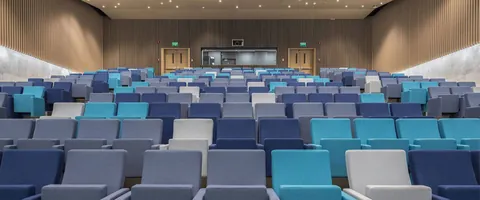 Rows of blue chairs on tiered risers in a hall