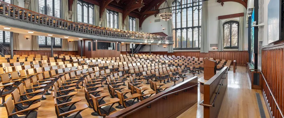 University lecture auditorium with tiered timber seating and writing tablets